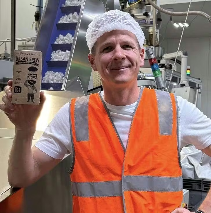 Urban Brew founder Toby Strong holding a box of Mind Blowing Intensity 14 coffee pods at our Australian production facility